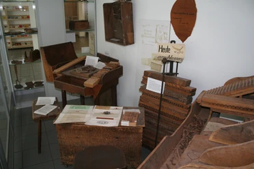 Ein kleiner Raum mit historischen Werkzeugen und Materialien zur Zigarrenherstellung in einer Ausstellung.