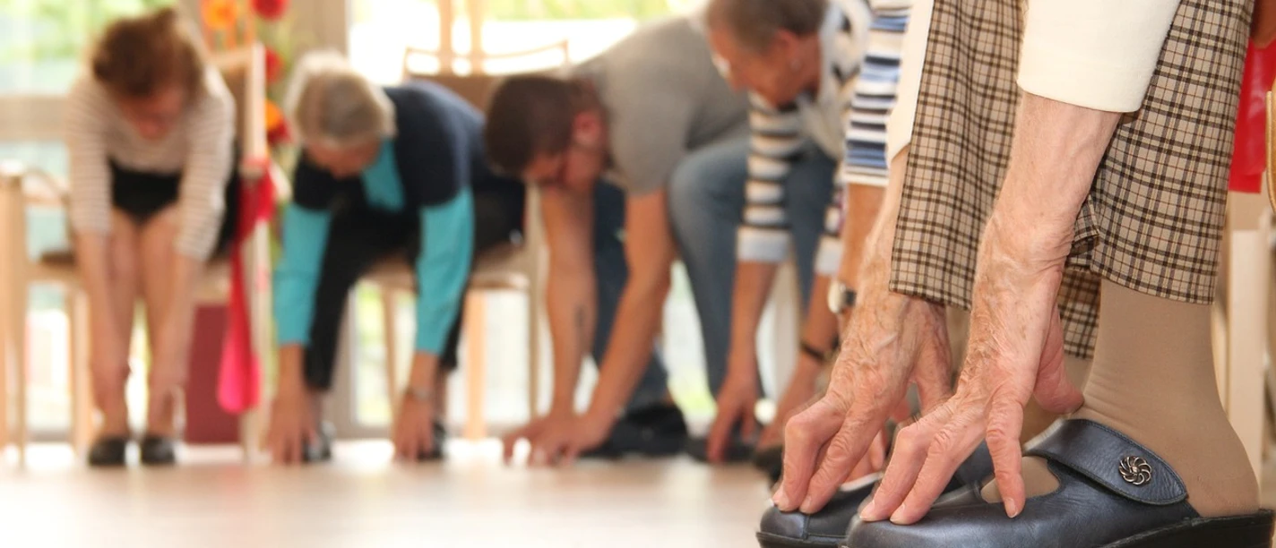 Seniorengymnastik Ältere Menschen führen gemeinsam in einem hellen Raum Dehnübungen durch, unterstützen ihre Beweglichkeit.