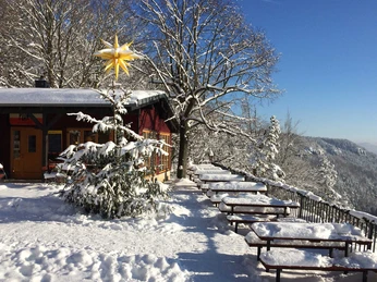 Brand-Baude im Winter Verschneite Berghütte mit leuchtendem Stern, umgeben von Schneeflocken, Tischen und Bänken.Snow-covered mountain hut with a shining star, surrounded by snowflakes, tables and benches.Zasněžená horská chata se zářící hvězdou, obklopená sněhovými vločkami, stoly a lavicemi.Pokryta śniegiem górska chatka z błyszczącą gwiazdą, otoczona płatkami śniegu, stołami i ławkami.Besneeuwde berghut met een stralende ster, omringd door sneeuwvlokken, tafels en banken.Baita di montagna innevata con una stella splendente, circondata da fiocchi di neve, tavoli e panche.