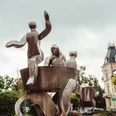 Brunnen "Auf dem Düvelsdreck" Metallskulptur mit abstrakten Figuren, umgeben von Bäumen und Gebäuden im Zentrum von Bad Nenndorf.