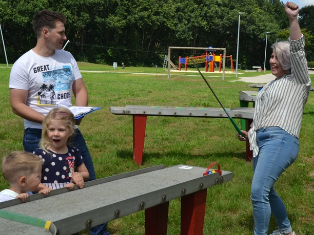 PitPat Hümmlinger Land Eine Frau jubelt beim PitPat-Spiel mit Familie auf einer grünen Rasenfläche im Hümmlinger Land.