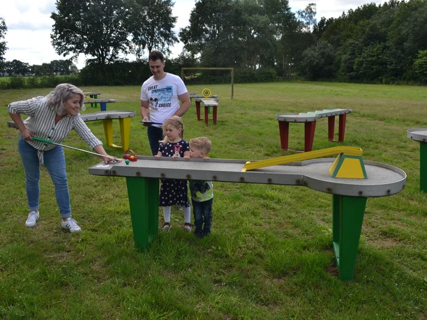 PitPat Hümmlinger Land Familie spielt gemeinsam PitPat auf einer grünen Wiese mit bunten Spieltischen im Hümmlinger Land.