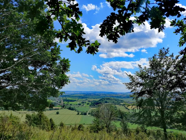 Weids uitzicht over groene velden en glooiende heuvels van de Leine vallei onder een blauwe lucht met witte wolken