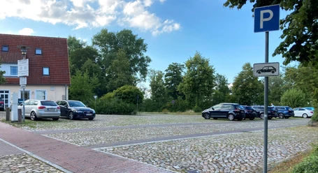 Parkplatz_MoellnerStr1_22082023_PetraRoemer.jpg Parkplatz mit Stellflächen, geparkten Autos und Hinweisschildern