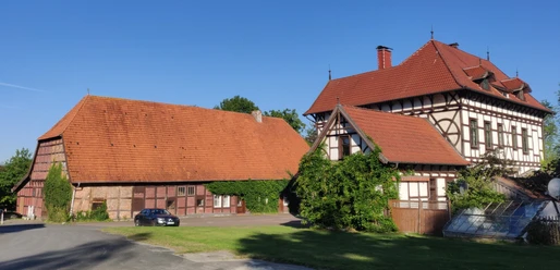 HRenerig Gutshof + alte Vogtei.jpg Gutshof mit Fachwerkhaus und Scheune unter blauen Himmel, rote Dächer und grüne Vegetation.