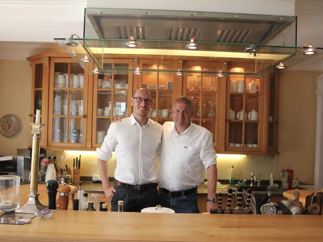 WEB1.JPG Innenraum der Villa Martha, zwei Männer stehen hinter der Theke, Einrichtung und Dekoration sichtbar