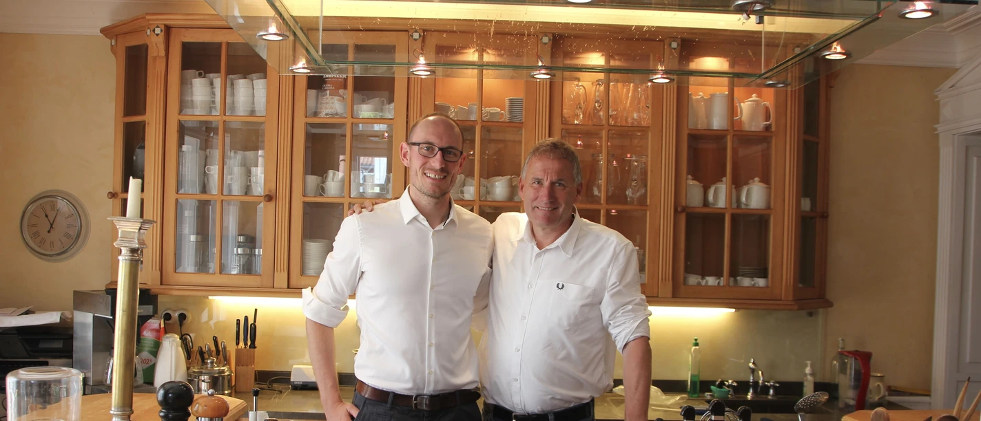 WEB1.JPG Innenraum der Villa Martha, zwei Männer stehen hinter der Theke, Einrichtung und Dekoration sichtbar