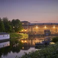 Wasserkraftwerk Raffelberg, Mülheim an der Ruhr Wasserkraftwerk Raffelberg in der Abenddämmerung, umgeben von Wasser und üppigem Grün.
