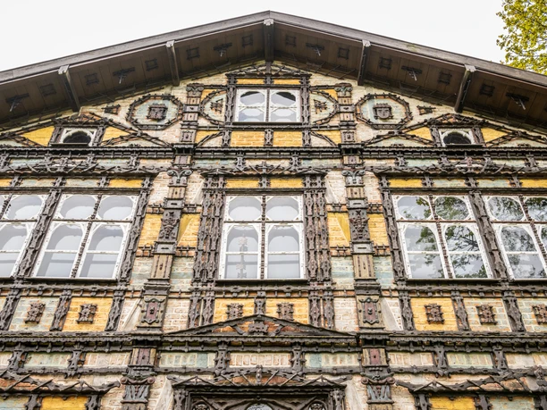 Fachwerkgebäude mit detaillierten Verzierungen und großen Fenstern, Symmetrie in der Fassadengestaltung.