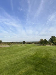 Golf Park Steinhuder Meer Uitgestrekte golfweide met een diepblauwe lucht, omringd door verspreide bomen aan de horizon.