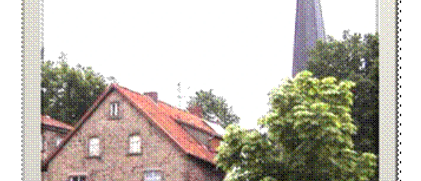 Ferienwohnung Capella.gif Ein Backsteinhaus mit grünem Baum im Vordergrund, dahinter ein Kirchturm in ländlicher Umgebung.