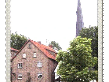 Ferienwohnung Capella.gif Ein Backsteinhaus mit grünem Baum im Vordergrund, dahinter ein Kirchturm in ländlicher Umgebung.