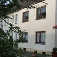 Ferienwohnung Grünwald.JPG Mehrfamilienhaus mit verputzter Fassade, mehreren Stockwerken und einfachen Fenstern, umgeben von Bäumen.