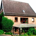 Ferienwohnung Merkord.JPG Ein Ziegelbau mit Satteldach, umgeben von grüner Vegetation, bietet Pflanzendekor an Fenstern und Terrasse.