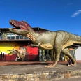 Dinopark-Münchehagen Ein lebensgroßes Dinosauriermodell steht vor einem roten Gebäude im Dinopark Münchehagen.