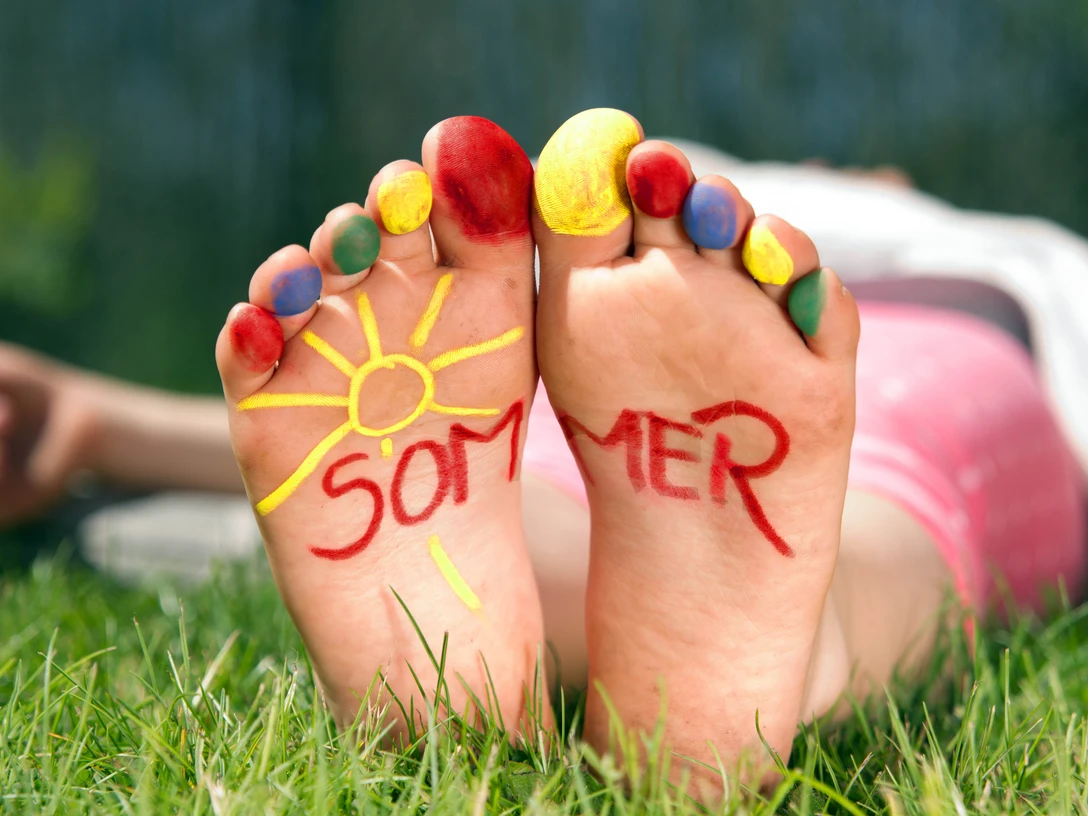 Spielen_im_Park.jpg Barfuß im Gras mit bunten Zehen, auf den Fußsohlen steht das Wort Sommer neben einer Sonne.