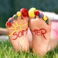 Spielen_im_Park.jpg Barfuß im Gras mit bunten Zehen, auf den Fußsohlen steht das Wort Sommer neben einer Sonne.