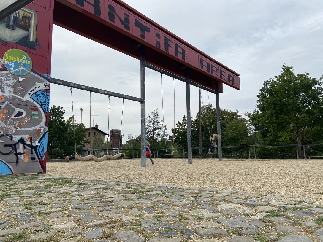 Bürgerbahnhof Plagwitz - Familienurlaub in Leipziger Industriedenkmal Zwei Schaukeln, die an einem ehemaligen Verladearm am EIngang des Bürgerbahnhofs hängen