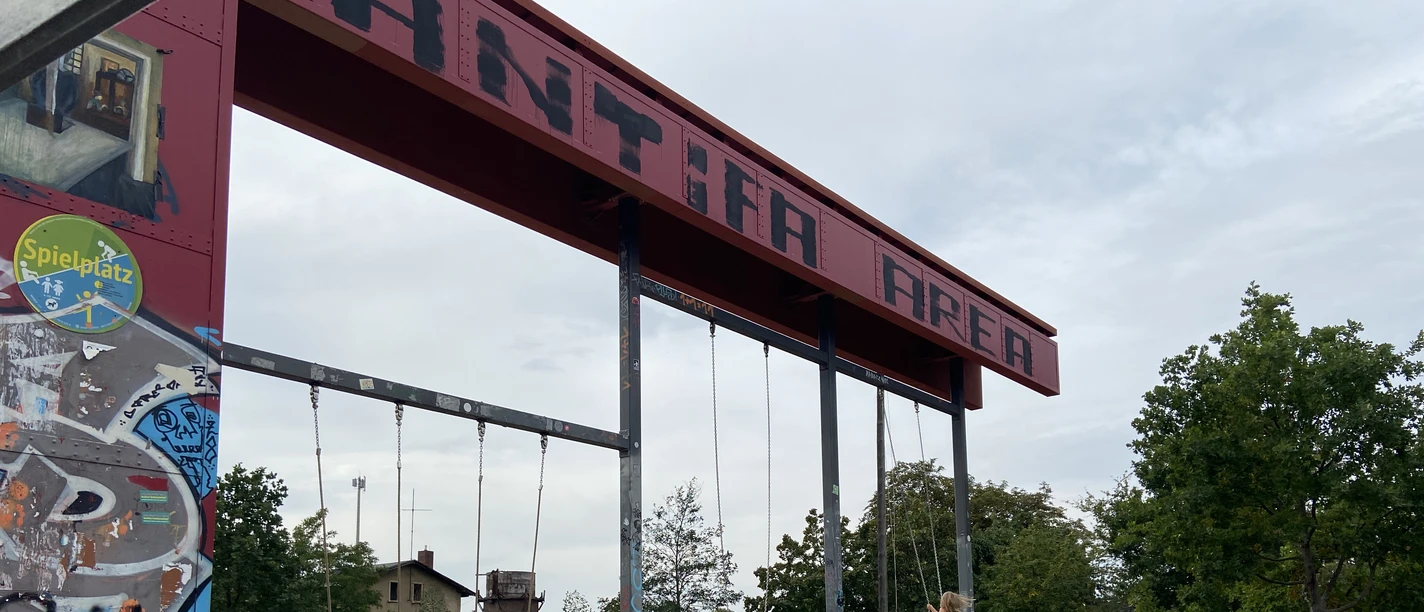 Bürgerbahnhof Plagwitz - Familienurlaub in Leipziger Industriedenkmal Zwei Schaukeln, die an einem ehemaligen Verladearm am EIngang des Bürgerbahnhofs hängen