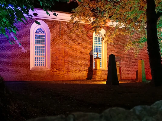 Lichtertage: Kirche Greetsiel Zu sehen ist die beleuchtete Kirche Greetsiel von außen, in rötliches Licht getaucht.