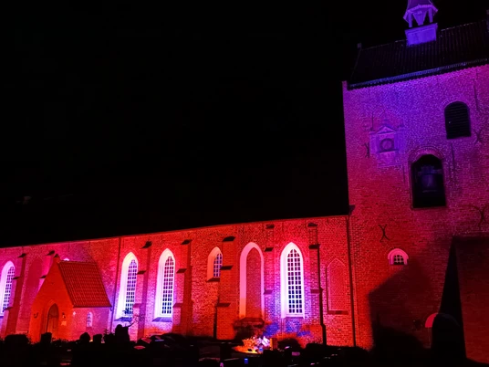 Lichtertage: Kirche Groothusen Zu sehen ist die beleuchtete Kirche in Groothusen, in Rot-Töne getaucht.