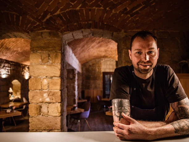 genussatelier-dresden-2.jpg Ein Koch im Restaurant mit Gewölbedecke und einladendem Ambiente in warmen Tönen.