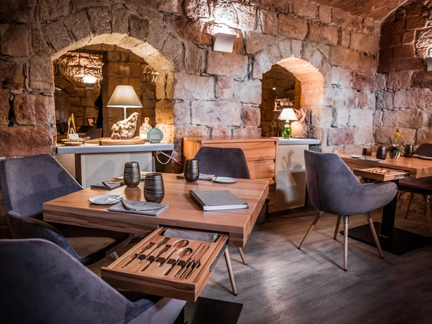 genussatelier-dresden-4.JPG Ein eleganter Speiseraum mit Steinwänden und modernen, bequemen Stühlen.