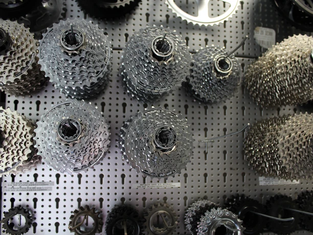 Zahnräder Verschiedene Fahrradritzel und Zahnräder hängen ordentlich an einer perforierten Werkzeugwand.