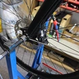 Radreparatur Ein Fahrrad wird auf einem blauen Halter für Wartungsarbeiten fixiert, Werkzeug ist im Hintergrund sichtbar.