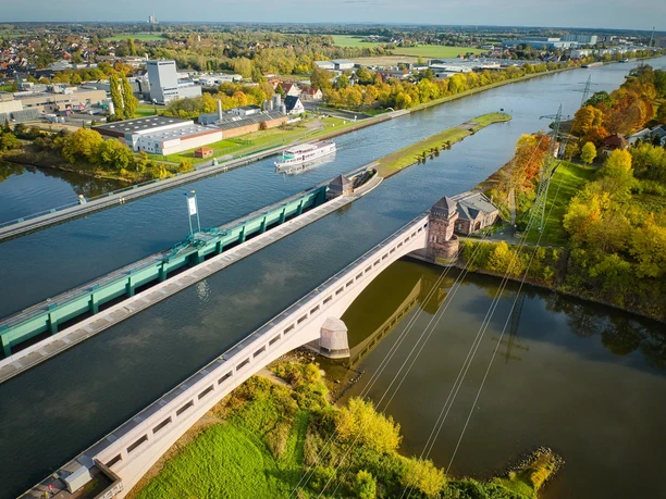 Das Bild zeigt das Wasserstraßenkreuz von oben. Auf dem Mittellandkanal fährt ein Schiff der Mindener Fahrgastschiffahrt.