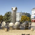 Ebertplatz Der Ebertplatz in Köln zeigt einen modernen Brunnen mit Wassertrommeln und einer zentralen Säule. Umgeben von Bäumen und Gebäuden, bietet er eine urbane Kulisse an einem sonnigen Tag. Ebertplatz in Cologne features a modern fountain with water drums and a central column. Surrounded by trees and buildings, it provides an urban backdrop on a sunny day.