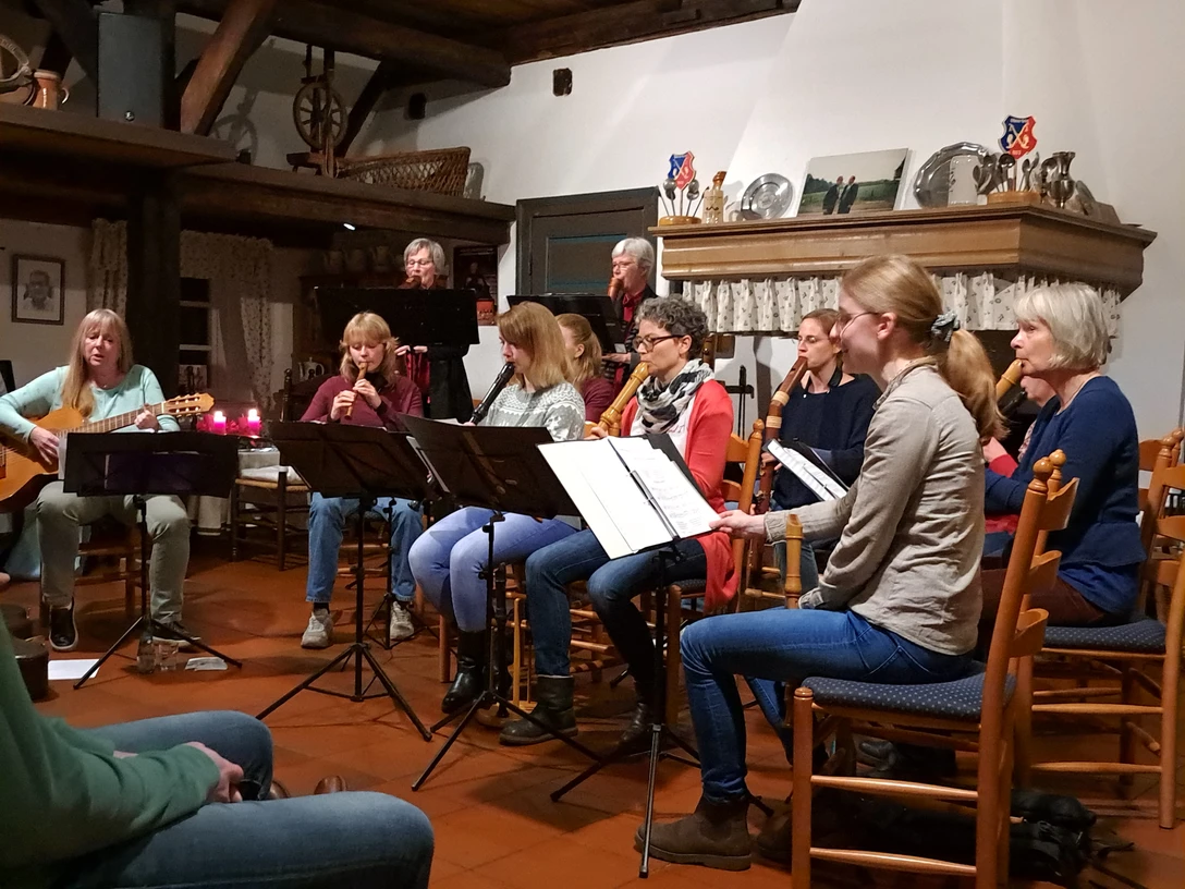 20221205_202524.jpg Eine Gruppe spielt Musik im Raum. Frauen sitzen mit Flöten und Gitarre zusammen.