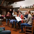 20221205_202524.jpg Eine Gruppe spielt Musik im Raum. Frauen sitzen mit Flöten und Gitarre zusammen.