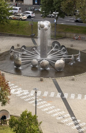 Ebertplatz Der Ebertplatz in Köln zeigt eine eindrucksvolle Brunneninstallation mit sphärischen Elementen, Bäumen, gepflasterter Fläche.Ebertplatz in Cologne features an impressive fountain installation with spherical elements, trees and a paved surface.