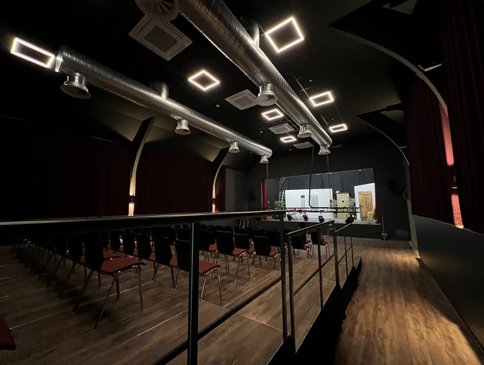 Ein moderner Veranstaltungsraum mit industriellen Lüftungsrohren und reihenweise angeordneten Sitzen.