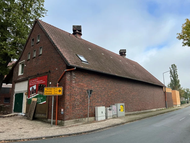 Heimatscheune Martfeld, ein rotes Backsteingebäude mit Satteldach an einer ruhigen Straßenkreuzung.