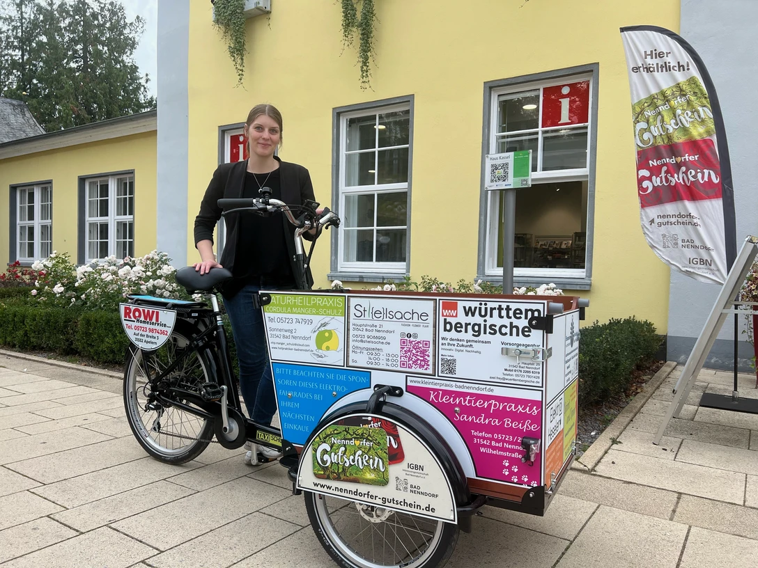 Ein Lastenrad von Babboe mit Werbeaufdruck vor einem gelben Gebäude in Bad Nenndorf.