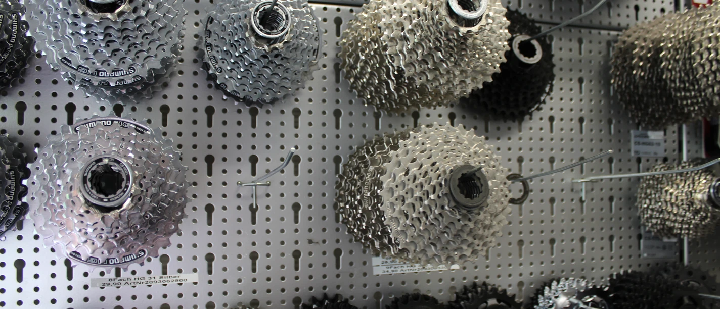 Zahnräder Fahrradzahnräder verschiedener Größen hängen an einer Lochwandtafel in einem Fahrradgeschäft.