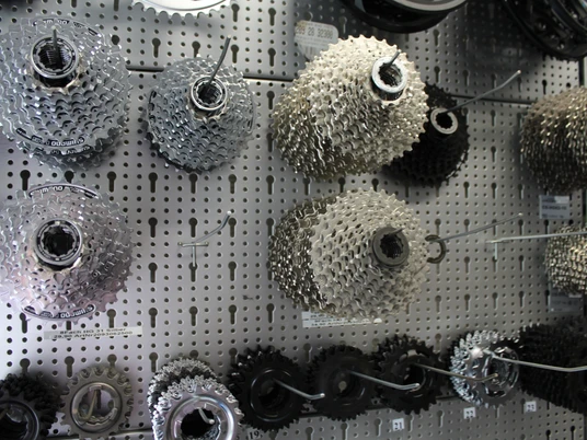 Zahnräder Fahrradzahnräder verschiedener Größen hängen an einer Lochwandtafel in einem Fahrradgeschäft.