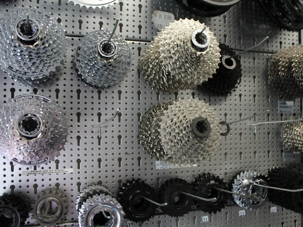 Zahnräder Fahrradzahnräder verschiedener Größen hängen an einer Lochwandtafel in einem Fahrradgeschäft.