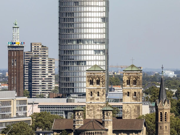 KölnTriangle The picture shows the KölnTriangle, a modern, cylindrical office tower surrounded by historic and modern Cologne architecture.