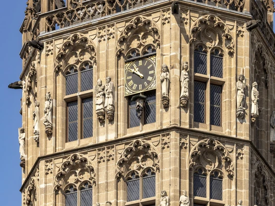 Platzjabbeck Detailaufnahme des mittelalterlichen Glockenturms des Historischen Rathauses Köln mit reichhaltigem Fassadenschmuck und prominenter Uhr in der Mitte.Close-up of the medieval bell tower of Cologne's historic town hall with richly decorated façade and prominent clock in the middle.