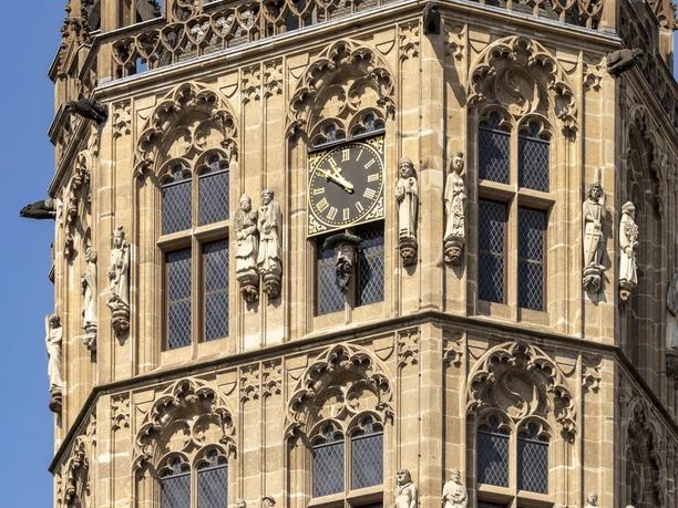 Platzjabbeck Close-up of the medieval bell tower of Cologne's historic town hall with richly decorated façade and prominent clock in the middle.