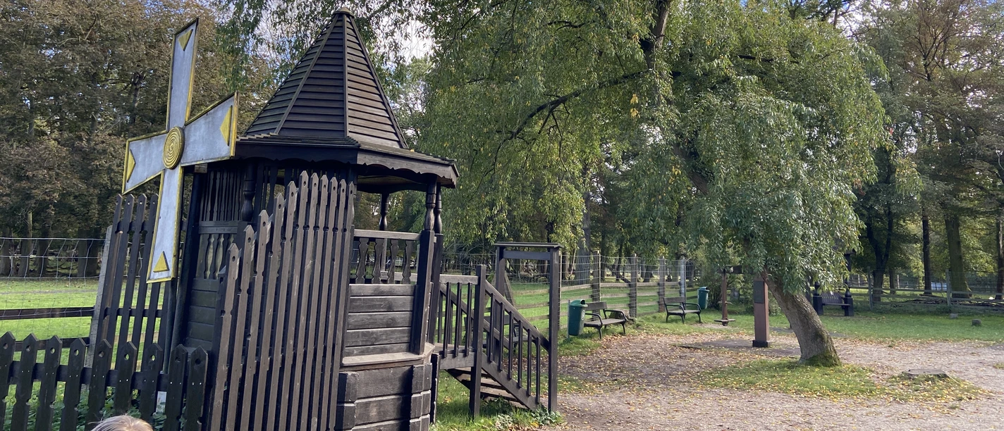 Ciemny drewniany sprzęt do zabawy w rosyjskim domku z bali pięknie komponuje się z naturalnym otoczeniem.