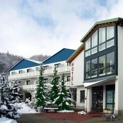 Hotelgebouw in de winter, met besneeuwde bomen en een blauw dak; heldere, koude sfeer.