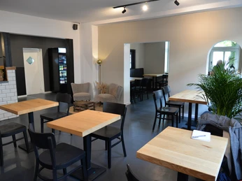 WIDU Gastraum Moderner Gastraum mit Holztischen und schwarzen Stühlen, umgeben von sanften, hellen Wänden.