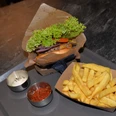 Burger mit Salat, Tomaten und Zwiebeln, serviert mit Pommes frites, Sauce und Ketchup auf Tablett.