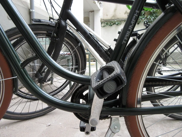 Fahrrad Zwei Fahrräder mit braunen Reifen stehen nebeneinander auf einer betonierten Fläche, im Vordergrund eine Pedale.