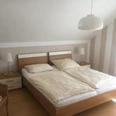 Schlafzimmer FeWo Brüggemann Helles Schlafzimmer mit modernem Doppelbett, Nachttischen aus Holz und sanfter Beleuchtung.
