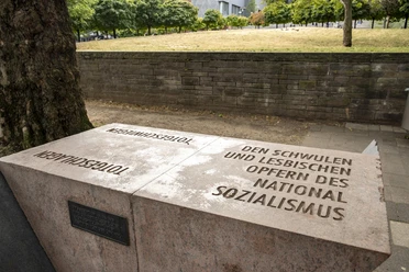 Rosa-Winkel-Mahnmal Steinernes Mahnmal in Köln mit Aufschrift für schwule und lesbische NS-Opfer vor Baum.